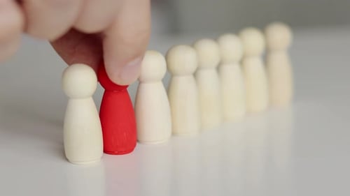 Leadership, career growth. Red figure in row of many wooden people figures.