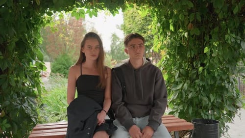 Two Teenagers Exchanging Glances Beneath Vinecovered Archway in Peaceful Garden Serene Summer Moment