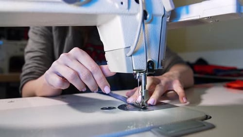 Process of sewing fabric on a sewing machine. Tailor working with sewing machine at workshop.