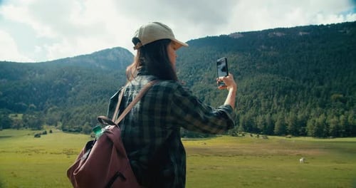 Female Traveler on Hike Path Take Photo with Mobile Phone of Mountain Landscape
