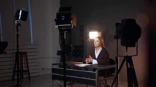 Beautiful Caucasian woman sits at desk talking to camera.