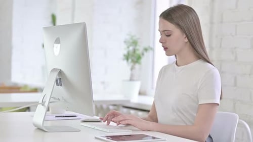 Ehrgeizige junge Frau arbeitet im Büro am Desktop