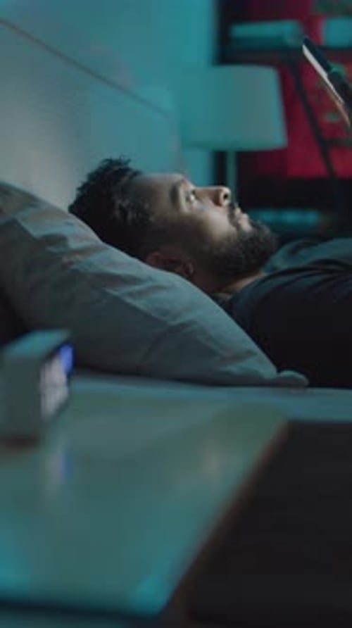 Young Adult Uses Phone in Bed Then Sleeps