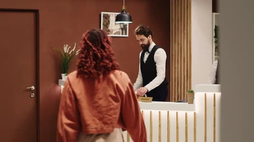 Hotel Receptionist Assists Guests at Front Desk