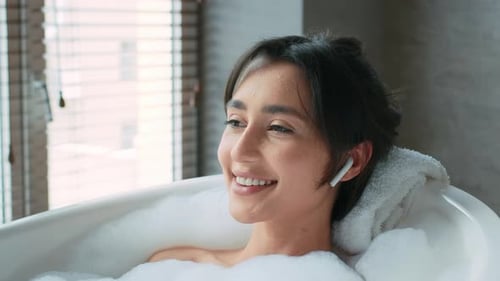 Woman Relaxing in Bubble Bath with Wireless Earbuds