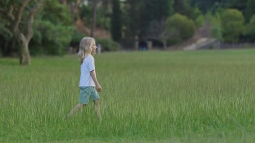 Blond Child Walking in a Green Meadow