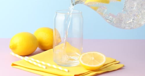 Pouring Refreshing Lemonade into Glass with Yellow Straw