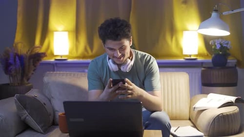Young Adult Smiling and Using a Cellphone Indoors