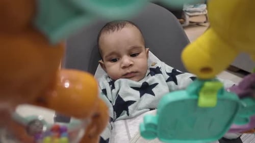 Infant Sits in Baby Seat with Toys