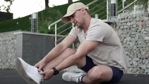 A man feels acute pain in his ankle joint and massages his painful leg during an evening walk.