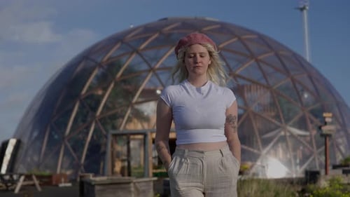 Confident Woman Stands Before Geodesic Dome on Sunny Day