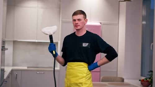 Young Adult Holding Handheld Steamer in Kitchen