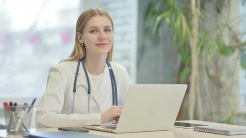Female Doctor Working on Laptop and Smiling