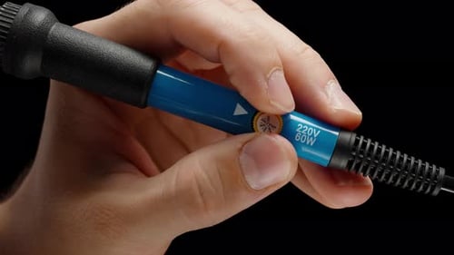 Blue Soldering Iron Sixty Watt and Two Hundred Twenty Volts in Man's Hands, Adjusting Power.