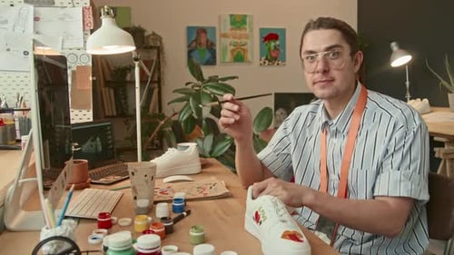 Young Adult Customizing Fashion Sneakers With Art
