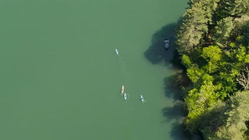 A Birdseye view of people kayaking and fishing on a lake near a forest in Wisconsin, USA. It's a bri