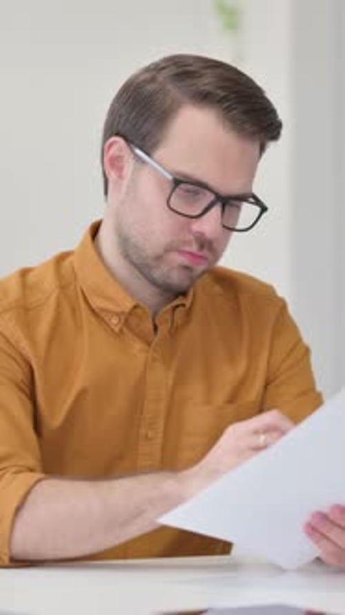 Man Reviews Documents at Desk Indoors
