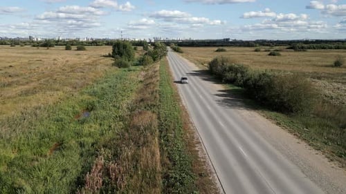 A Beautiful Scenic Rural Road Stretches Under a Bright Blue Sky Adorned with Fluffy Clouds Clip