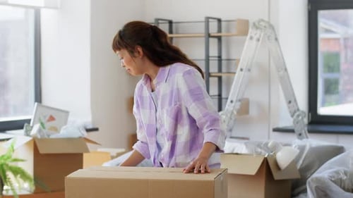 Moving, People And Real Estate Concept - Happy Smiling Asian Woman With Adhesive Tape Packing Box...