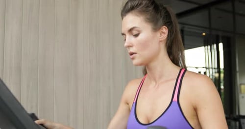 Sporty Woman on Elliptical Trainer in the Gym
