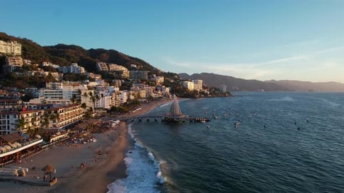Puerto Vallarta riviera at sunset with oceanfront hotels and resorts on the mountain, aerial