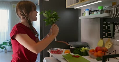 Woman Singing and Dancing with Vegetables in Kitchen