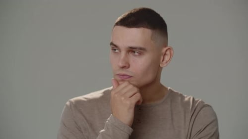 A Young Man Looks Around and Rubs His Chin While Thinking About Something Closeup Shot of a Pensive