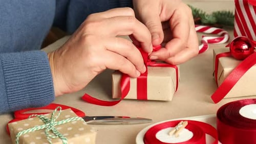 Hands Tying Red Ribbon on Christmas Gift