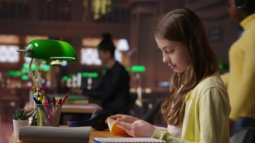 Focused Schoolgirl Reading a Book in the Library for Mandatory Literature