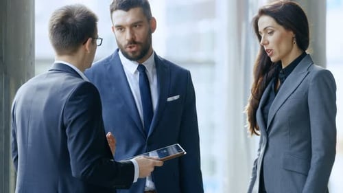 Male and Female Business People Use Tablet Computer and Discuss Investment Ideas while Standing on