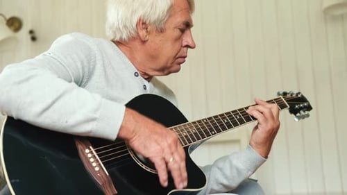 Senior Man Plays Acoustic Guitar at Home