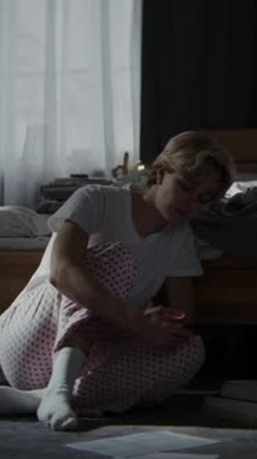 Woman Surrounded By Papers Scrolls Newsfeed on Smartphone