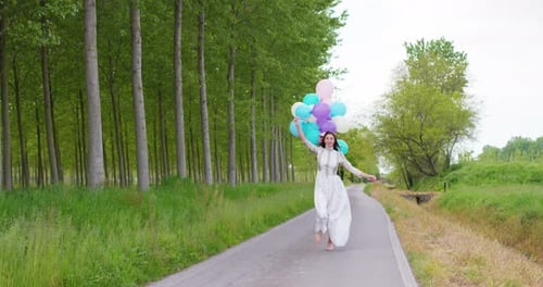 Woman Runs Barefoot with Balloons on Rural Road