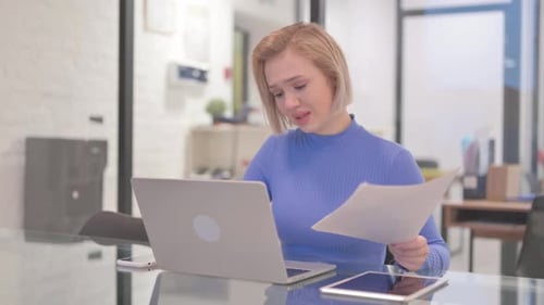 Young Woman Frustrated by Documents at Desk