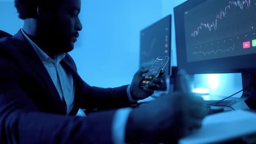Business African trader investor using stock exchange market app on mobile inside office at night