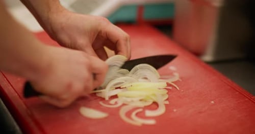 Chef Slicing Onions on a Red Cutting Board