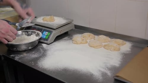 A Closeup of a Chef Weighing Equal Pieces of Burger Bun Dough on a Scale