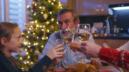 Family cheers glasses at Christmas dinner table