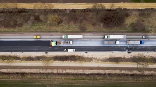 Trucks Full of Hot Asphalt and Paver Aerial View of New Road Construction Repair Work on Highway