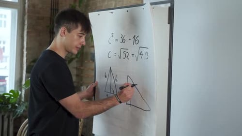 Side view. Serious dark hair male European asks students to solve the geometry math task with group