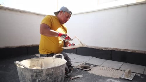 worker making cement in a bucket to pave terrace
