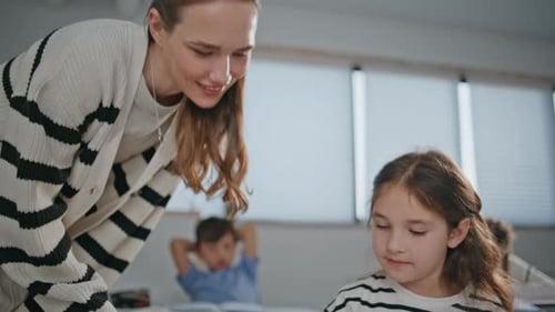 Teacher Helping Student with Assignment in Classroom