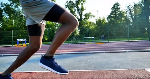 Primer plano a cámara lenta de un joven atleta africano realizando un salto de longitud en una pista de carreras en Athl