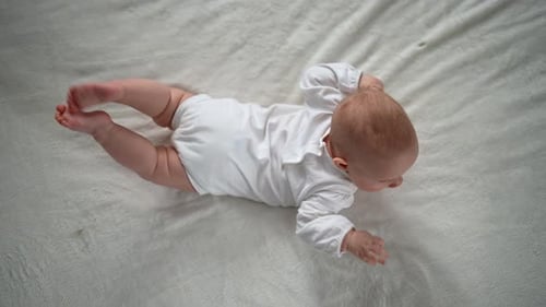 Top View of Cute Little Newborn Girl Crawling on Bed in Bedroom Infant Baby Resting Playing Lying