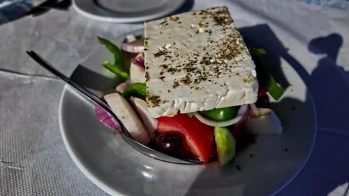 Gros plan d'une salade grecque fraîche au fromage feta par une journée ensoleillée avec des femmes profitant de ses vacances, par