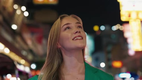 Curious Young Woman Looks Around on Night City Street