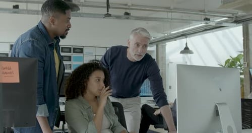 Group of Coworkers Meeting round a Desktop Computer in Discussion