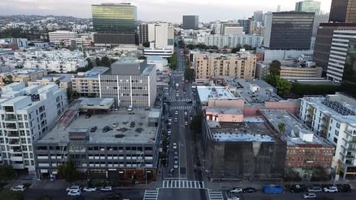 Push in drone shot with bird's eye view of building roof tops and cityscapes in the distance.