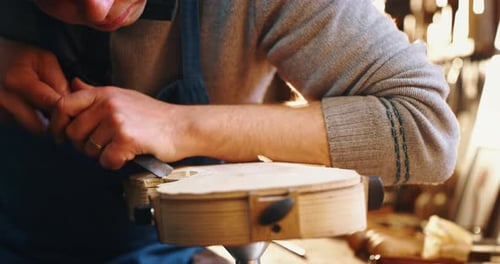 Slow motion close up of master artisan luthier painstaking detailed work on wood violin in a works