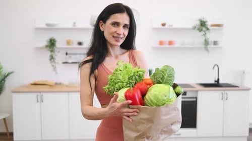 Fit Lady Posing at Home with Bag of Greens and Vegetables